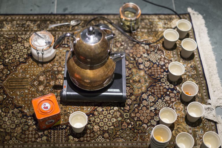 A gold-colored tea set arranged on a floor mat
