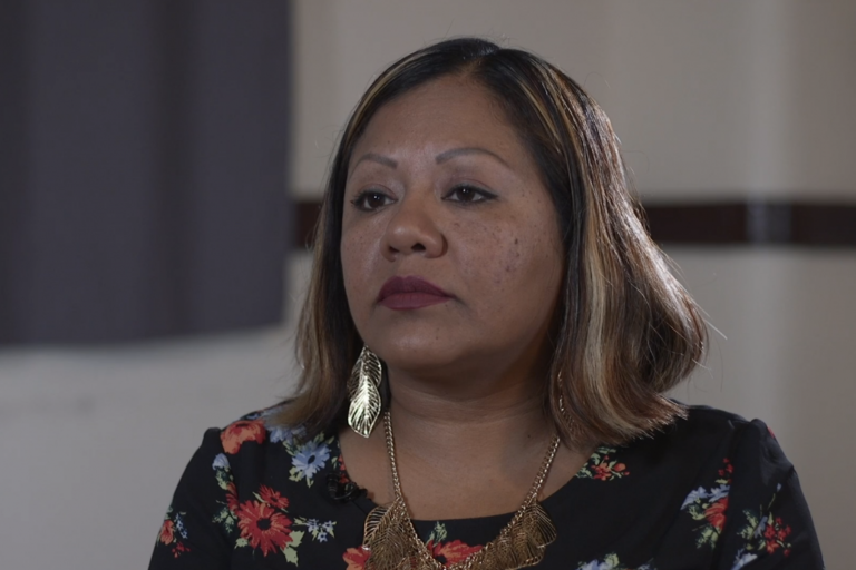 A woman in a floral shirt looks to the left of the camera